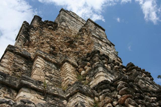 A low-angle view of the imposing upper section of El Castillo, partially damaged by Hurricane Gilbert in 1988.
