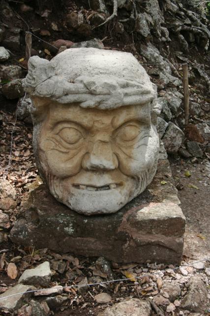 The gigantic head of a Pauahtun, a mythical being part man and part crocodile, on the ground at the Eastern base of Temple 11.